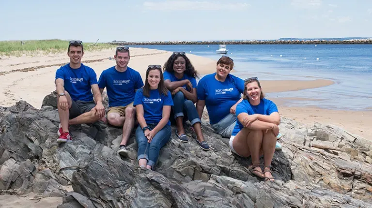 Group of U N E students sitting on a rock at the beach